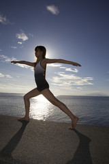 Fototapeta na wymiar Warrior Pose Yoga Girl by the Ocean