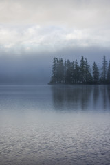 Fogg over lake side and forest with water reflection