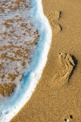 Fototapeta na wymiar traces of a woman's legs on the sandy beach