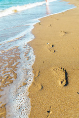 Fototapeta na wymiar traces of a woman's legs on the sandy beach