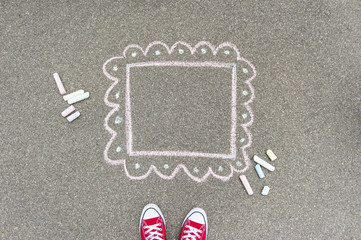 Feet in shoes on asphalt, with a chalk drawn frame