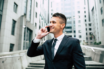 Handsome business man in full suit talking on phone outdoors
