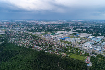 Aerial view of wheat fields, meadow, forest andindustrial warehouses in rural Russia.