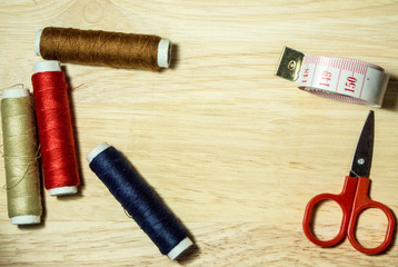 colorful thread , scissors and measuring tape on nature wooden background