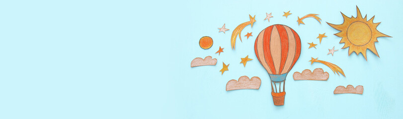 Banner of Hot air balloon, space elements shapes cut from paper and painted over wooden blue background.