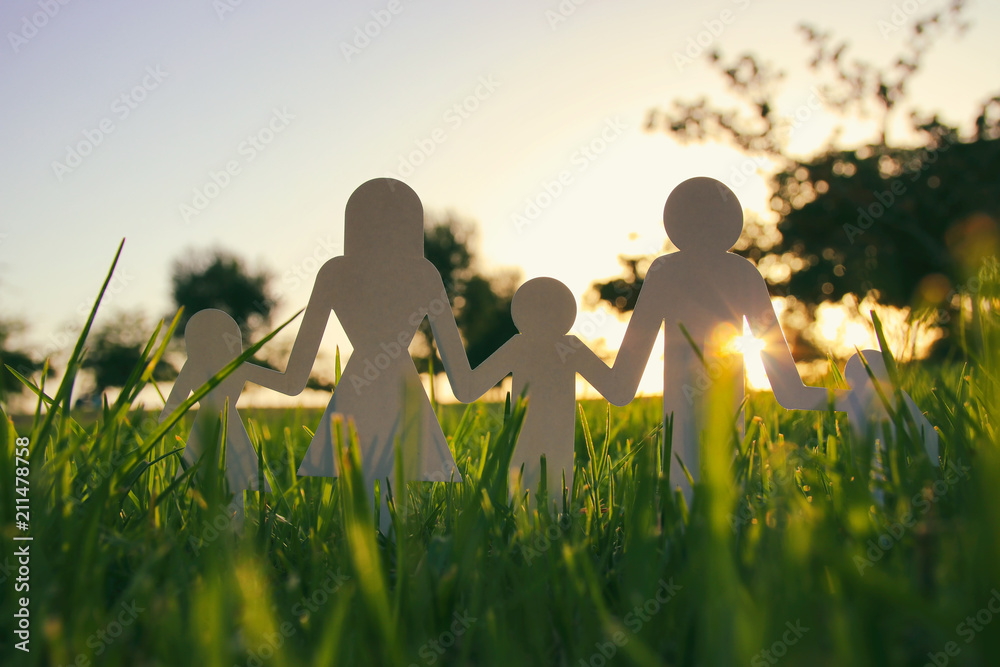 Wall mural image of happy family concept. paper cut people holding hands together in green grass during sunset.