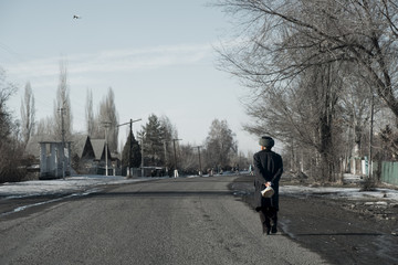 Kyrgyz grandfather walks along the road in the village and carries bread