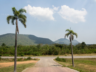 Fototapeta premium The road with the mountains in countryside on blue sky with clouds background