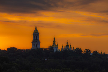 Fototapeta na wymiar Domes of Lavra Cathedral in Kiev, low angle. Yellow sunset background. Panoramic view.