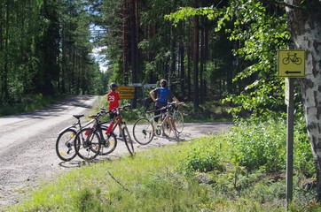 Family riding their bicycles looking for directions on signs in the forest