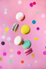 Sweet and colourful french macaroons flying in motion with confetti.