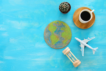 top view image of airplane , earth globe and coffee over blue wooden background.