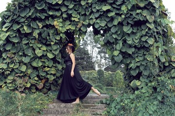 Slender brunette in a black dress in the park