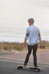 Back view of man riding an electric skateboard longboard 