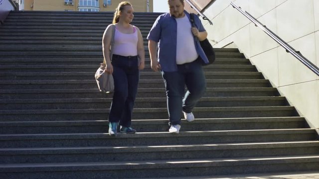 Obese couple walking on stairs, happy together, acceptance of person as he is