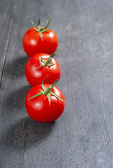 three red tomatoes on old black wooden table