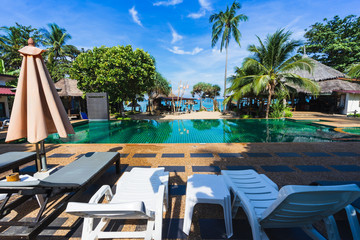 Pool chairs near the swimming pool and beach in the resort.