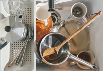 Full kitchen sink of dirty dirty dishes. Spoons, forks, cups, coffee maker, tableware.