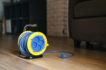 Electric Power Extension with blue wire and yellow drum in the interior of the apartment....