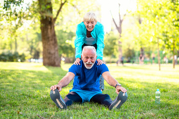 Happy fit senior couple exercising in park.