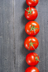 many tomatoes lined up on old black wooden table background