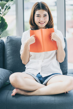 beautiful asian woman enjoy reading book on sofa home background
