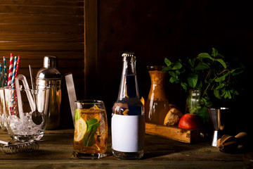 alcohol cocktail with fresh fruits and berries with a bottle of tonic and a place under the text on the bottle on wooden background