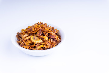 Deep fried shallots crisp / fried crispy onion flakes  (bawang goreng) in white bowl over wooden background.