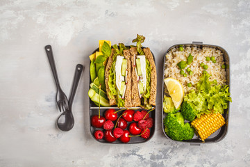 Healthy meal prep containers with feta sandwich with fruits, berries, rice and vegetables on white background, top view.