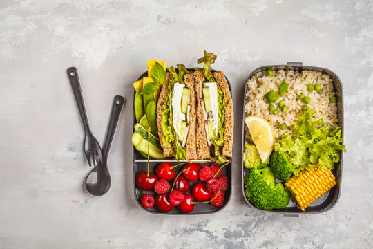 Healthy meal prep containers with feta sandwich with fruits, berries, rice and vegetables on white background, top view.