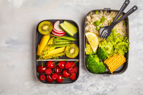 Healthy meal prep containers with brown rice, broccoli, vegetables, fruits and berries overhead shot with copy space