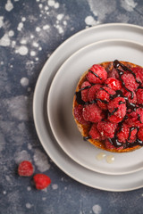 Homemade pancakes with raspberries on a gray plate, dark background, top view. Healthy vegan food concept.