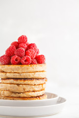 Vegan pancakes with raspberries and chia seeds on white plate, white background. Healthy vegan food concept.