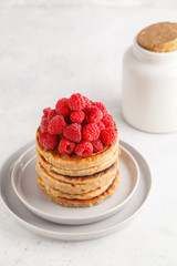 Vegan pancakes with raspberries and chia seeds on white plate, white background. Healthy vegan food concept.