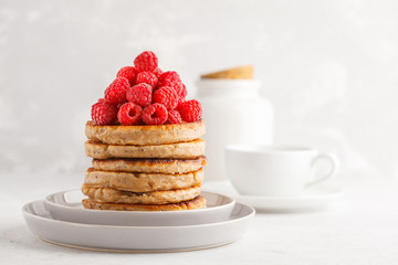 Vegan pancakes with raspberries and chia seeds on white plate, white background. Healthy vegan food concept. © vaaseenaa