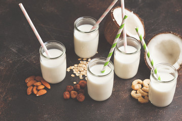 Vegan alternative nut milk in glass bottles on dark background. Healthy vegan food concept.