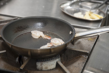 The hands of the cook, grilling shrimp