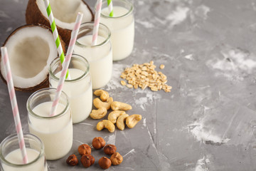 Vegan alternative nut milk in glass bottles on gray background. Healthy vegan food concept.