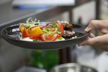 Hands cook, cooking lamb with vegetable garnish
