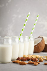 Vegan alternative nut milk in glass bottles on gray background. Healthy vegan food concept.