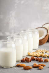 Vegan alternative nut milk in glass bottles on gray background. Healthy vegan food concept.