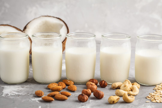 Vegan alternative nut milk in glass bottles on gray background. Healthy vegan food concept.