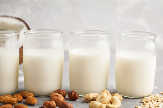 Vegan alternative nut milk in glass bottles on gray background. Healthy vegan food concept.