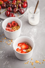 Homemade granola with yogurt and berries in small white bowls. Healthy food concept.
