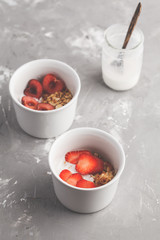 Homemade granola with yogurt and berries in small white bowls. Healthy food concept.