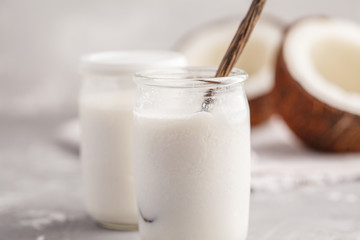 Homemade coconut yogurt in a glass jar on the table. Healthy alternative vegan food concept.