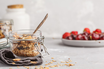 Fototapeta premium Homemade oat granola in glass jars with cherry and yogurt. Healthy food concept.