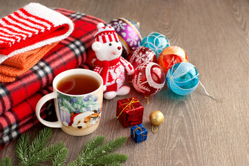 Bear, tea and plaid for the new year. A cup of tea with a New Year pattern, a funny bear toy, Christmas balls and a blanket create a cozy and festive mood for the new year.