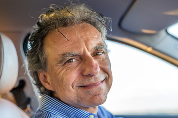 mature man smiling in a car