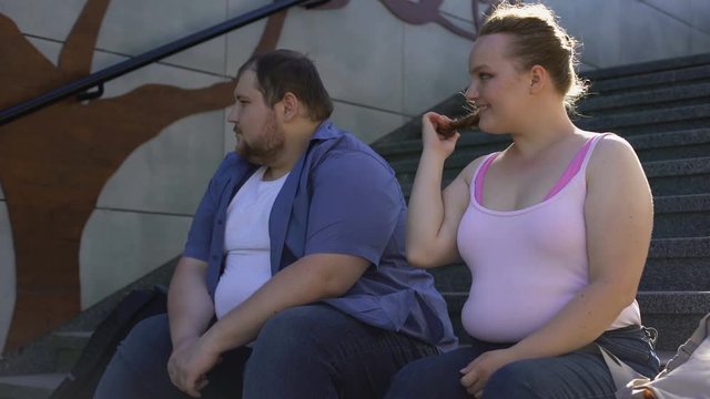 Obese cute girl flirting with young fat man, love in spite of imperfection